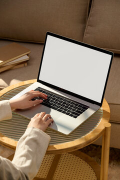 Person working on a laptop computer at home on a small wooden table