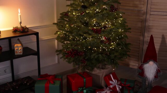 Beautiful Christmas tree, gift boxes and other festive decor indoors. Camera moving right and down