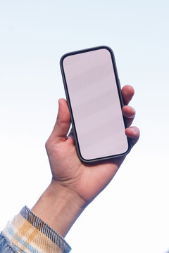 Hand of cropped man holding cellphone outdoors on white background