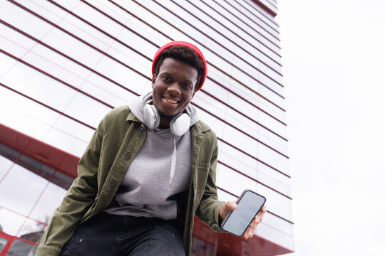 Bottom of smiling black man holding smartphone and looking at camera