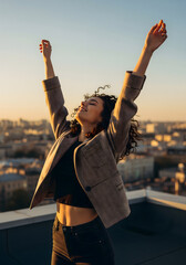 Woman with arms raised enjoying golden hour on a city rooftop