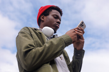 Bottom view of black concentrated man messaging or texting smartphone