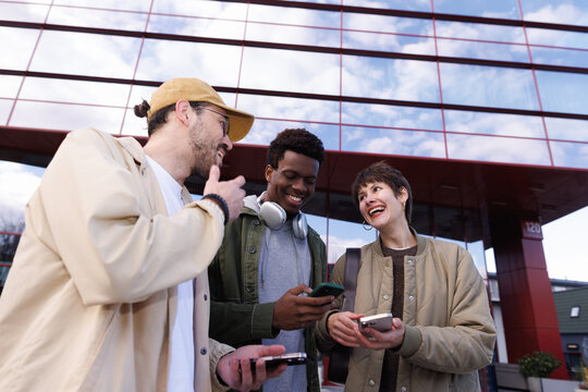 Pleased man and woman looking at each other while man using smartphone