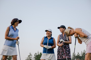 Candid moment of four women golfers sharing a joyful laugh 