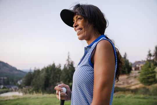 Candid outdoor portrait of a smiling woman with a golf club