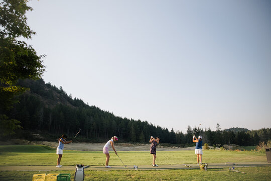 Candid golf practice on a sunny course with four players