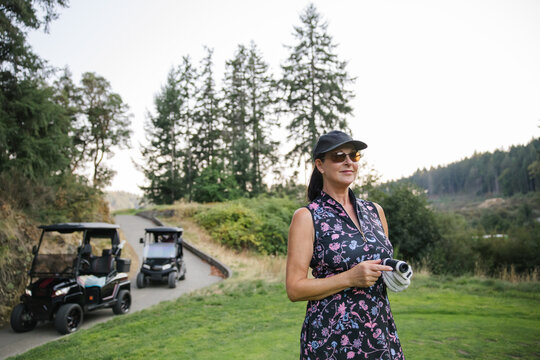 Candid outdoor scene: woman with camera, floral dress, golf cart