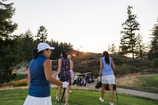 Candid group of friends golfing at sunset on a scenic course