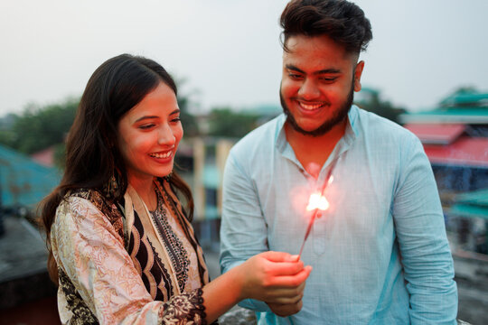Couple Celebrating a Joyful Evening With Sparkler on Rooftop
