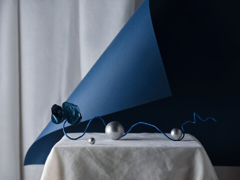 Abstract composition with silver spheres, blue paper and blue flower