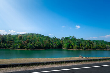 Scenic view of a serene lake Landscape surrounded by lush green forest under a clear blue sky.Nature Background