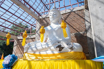 Damaged white Buddha situated in unfinished Viharn in countryside area of Chiang Rai province, Thailand.