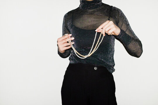 Person wearing party glitter shirt and shiny pearl necklaces in party