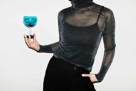 Person holding a cocktail glass and wearing party glitter shirt
