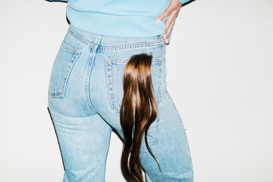 Person with ponytail hair extension on their jeans pocket with flash