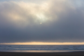 Seascape and setting sun through lifting fog