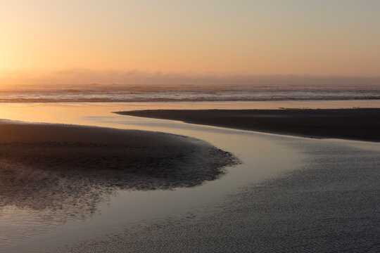 Expansive beach at sunset, tide pools in foreground