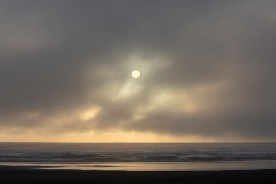 Seascape and setting sun through lifting fog