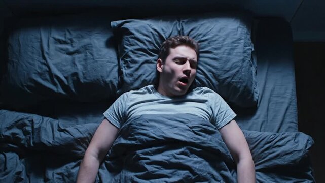 Man lying awake in bed at night with a worried expression