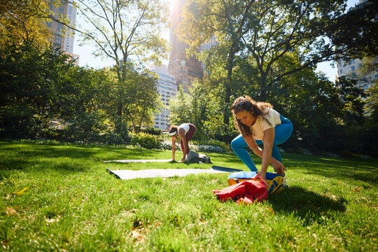 Friends get ready to do yoga in the park.