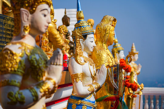 Traditional Thai celestial angel statues in prayer gesture at Wat Phra That Doi Kham temple on the mountain side of Chiang Mai, Northern Thailand