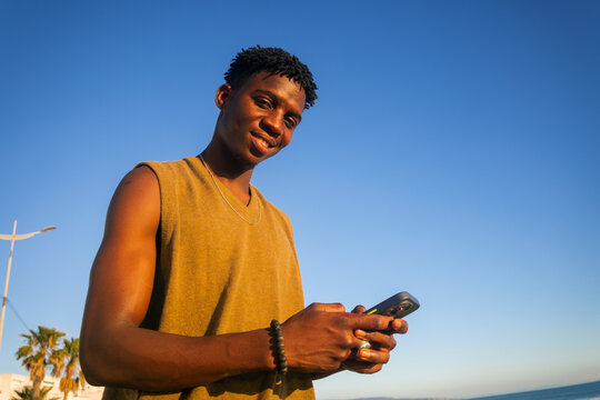Young Man Using Smartphone smiles to the camera