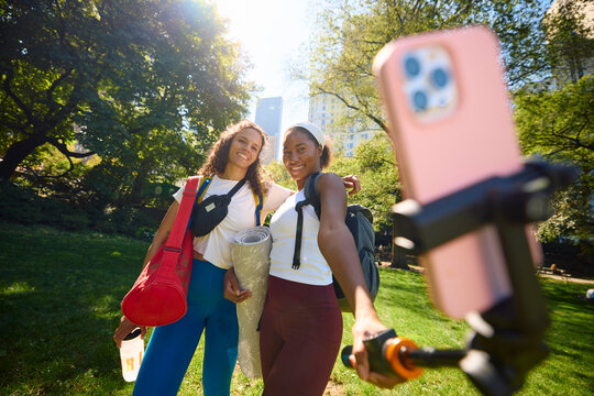 Female athletes snap selfies in the park.
