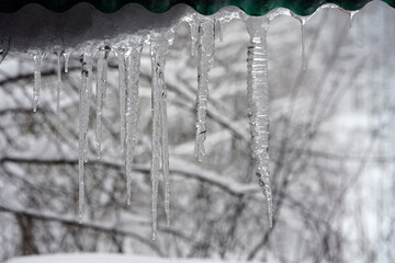 Close-up of long transparent icicles hanging from a roof in winter