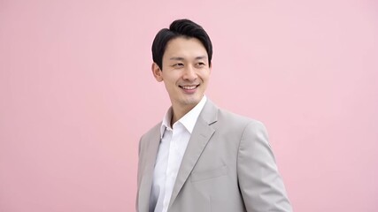 淡いピンクのグラデーション背景に立つ20代前半の若手ビジネスマン。
柔らかなハイキー照明が清潔感と前向きな印象を強調します。
新年度、新生活、キャリアスタートを想起させるビジュアル。