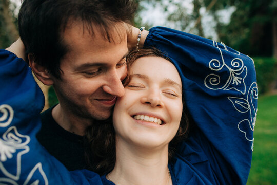 Couple smiling while embracing outdoors with eyes closed