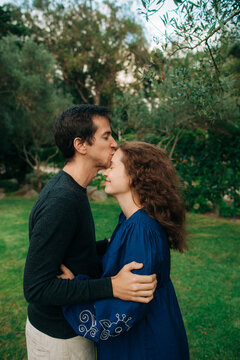 Man kisses forehead of smiling woman in garden