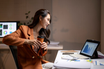Asian businesswoman analyzing data on tablet at night