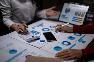 Business professionals analyzing financial data using charts and calculator