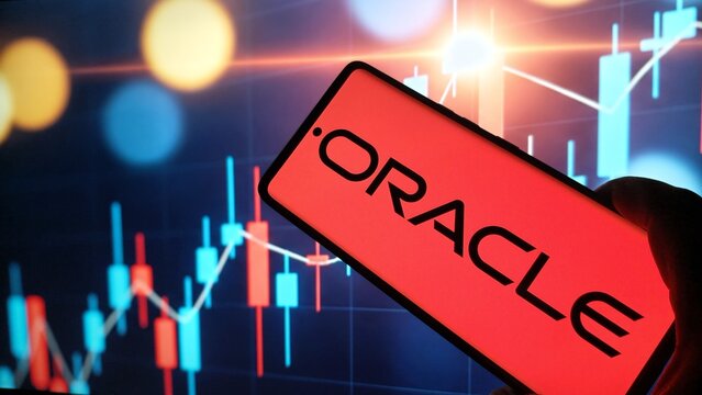 Hand holding smartphone with Oracle logo on screen displaying stock market graph