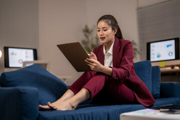 Businesswoman working late on couch reviewing charts