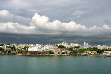 Epic waterfront view of Puerto Rico skyline beneath heavy dark clouds, foreground water