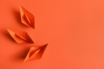 Naklejka premium Orange paper boats on color background