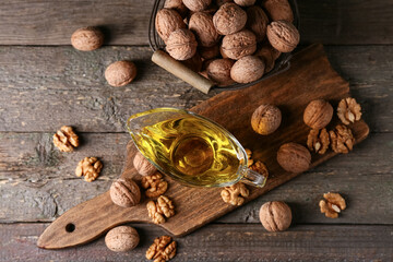 Gravy boat of fresh walnut oil and basket with nuts on wooden background
