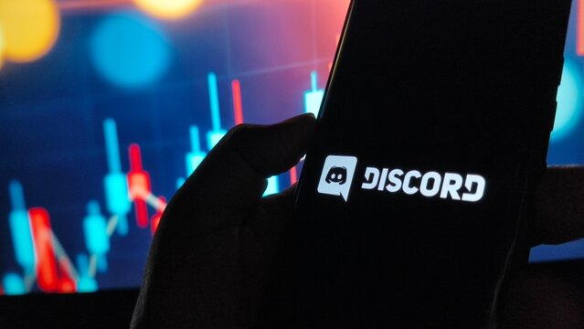 Hand holding smartphone with Discord logo on screen