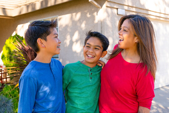 Smiling Family Enjoys a Sunny Day Outside Their Home Together