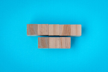 Set of five and three blank wooden square blocks, on blue surface.