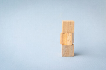 3 blank wooden square blocks stacked up on light blue background. Copy space.