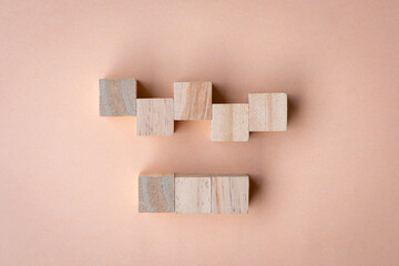 Set of five and three blank wooden square blocks on peach color surface.