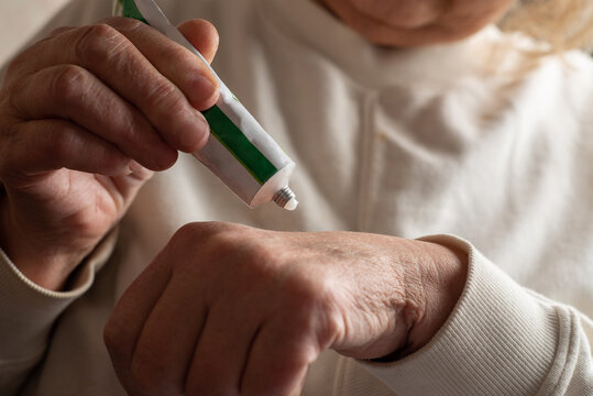 Anonymous woman squeezing ointment from tube onto hand