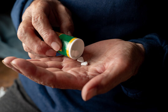 Two Pills and pill bottle in the hands of an elderly man