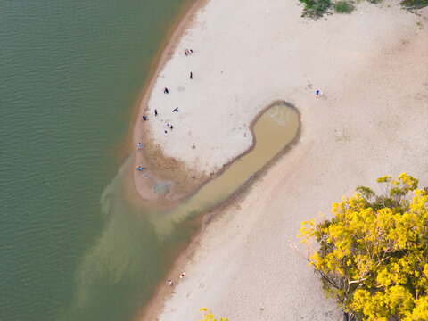 People on a sandy beach along side a shallow inlet