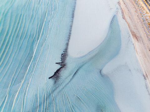 Waves sand patterns along a white sandy coastline