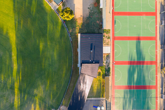 A row of netball courts alongside a green sports oval