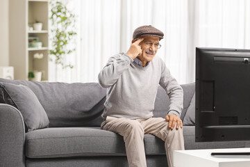 Senior man sitting on couch in front of TV