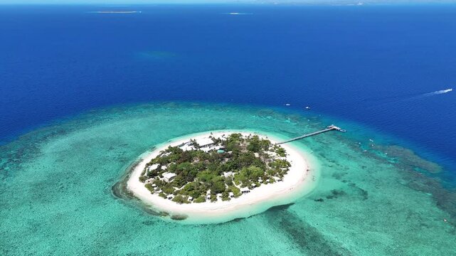 high-altitude aerial drone shot of Mala Mala Island in Fiji, showcasing the circular white sand beach and the surrounding turquoise coral reef lagoon.
